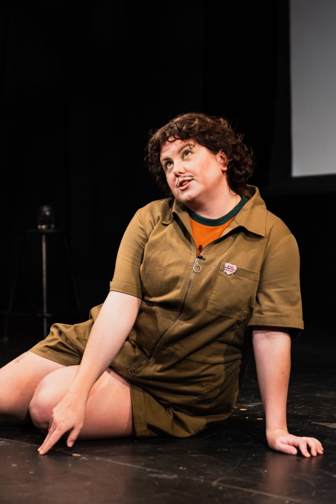 stevey sitting on a black box stage looking up into the air. 