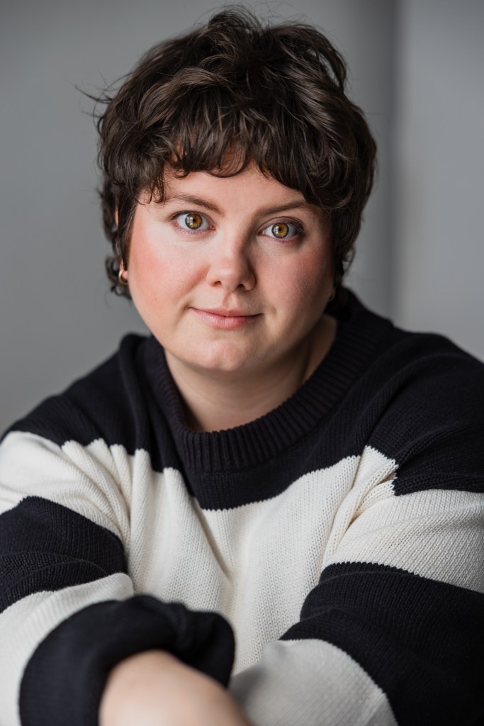 stevey hunter headshot wearing a striped white and black sweater looking straight into the camera. 